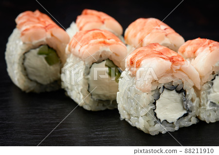 Sushi rolls california with snow crab, cream cheese, cucumber, sesame seeds and masago caviar isolateed on black background with reflection. Japanese oriental cuisine Sushi rolls california with snow crab, cream cheese, cucumber, sesame seeds and masago caviar isolateed on black background with reflection. Japanese oriental cuisine 88211910