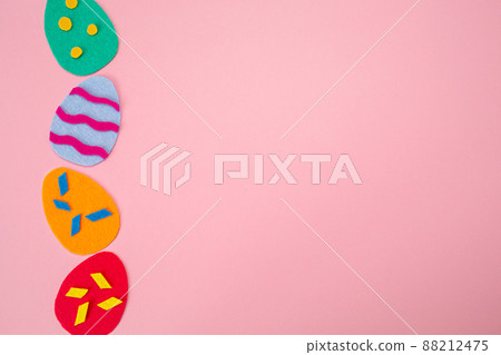 Easter decorations. Cut out of felt applications of colourful eggs on pink background. Flat lay. Copy space. Holiday concept Easter decorations. Cut out of felt applications of colourful eggs on pink background. Flat lay. Copy space. Holiday concept 88212475