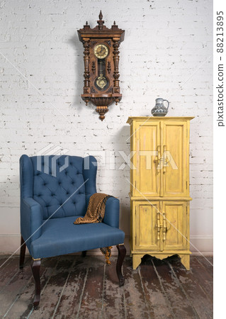 Vintage blue armchair, yellow cupboard, pendulum clock and orange scarf Vintage blue armchair, yellow cupboard, pendulum clock and orange scarf 88213895