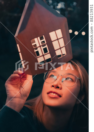 A Woman is looking at festive decoration light house lamp in winter festival new year celebration. 88213931