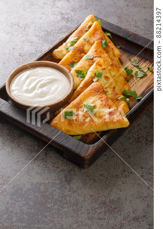 Triangular fried pancakes with meat served with sour cream close up on a wooden tray. Vertical Triangular fried pancakes with meat served with sour cream close up on a wooden tray. Vertical 88214397