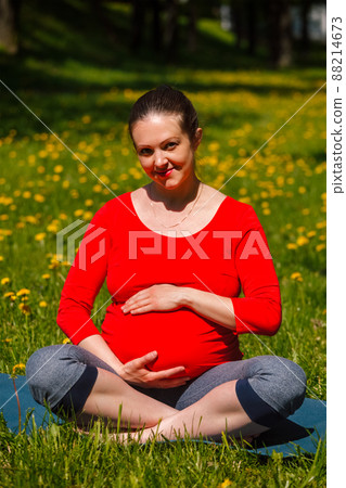Pregnant woman doing asana Sukhasana outdoors 88214673