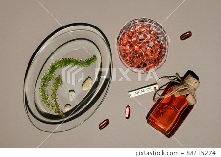 Glass bottle with algae oil, jelatin capsules and seaweed on brown paper 88215274