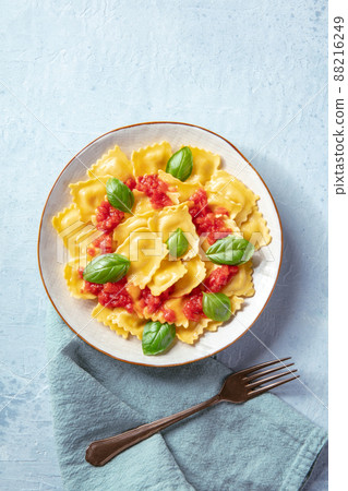 Ravioli with tomato sauce and fresh basil leaves, shot from above 88216249