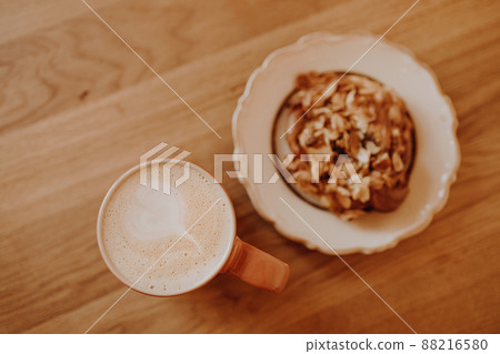 A cup of coffee and a fragrant bun on a wooden table in a city cafe 88216580
