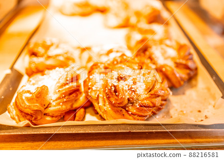 Several homemade baked Swedish cinnamon rolls or kanelbulle on a cooling rack at a cafe. 88216581