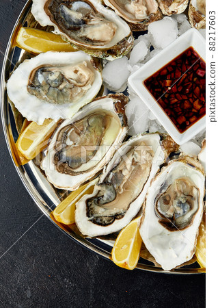 Oysters with lemon served on black round platter. Luxury delicatessen seafood. Oysters with lemon served on black round platter. Luxury delicatessen seafood. 88217603
