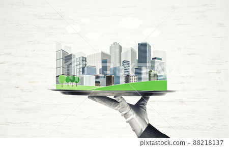 Hand holding metal tray with modern city model against wooden background Hand holding metal tray with modern city model against wooden background 88218137