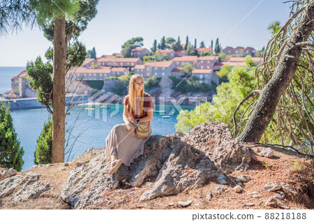 Woman tourist on background of beautiful view of the island of St. Stephen, Sveti Stefan on the Budva Riviera, Budva, Montenegro. Travel to Montenegro concept Woman tourist on background of beautiful view of the island of St. Stephen, Sveti Stefan on the Budva Riviera, Budva, Montenegro. Travel to Montenegro concept 88218188