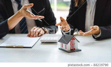 Businessman signs contract behind home architectural model. 88219790