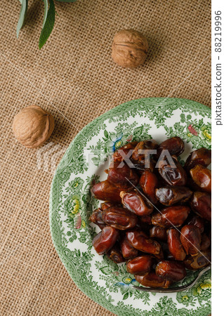 Dried dates in a green vintage plate on a brown textile background. Rustic style Dried dates in a green vintage plate on a brown textile background. Rustic style 88219996