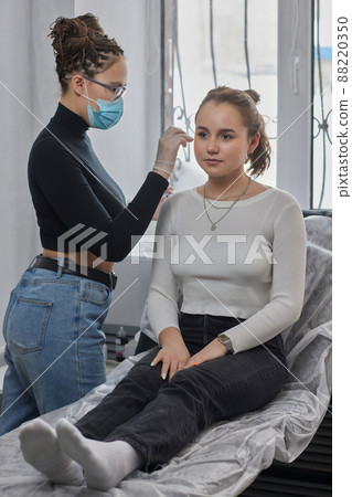 Stretched lobe piercing, grunge concept. Pierced woman ear with black plug tunnel. industrial and rook. 88220350