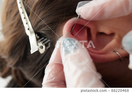 Stretched lobe piercing, grunge concept. Pierced woman ear with black plug tunnel. industrial and rook. 88220468