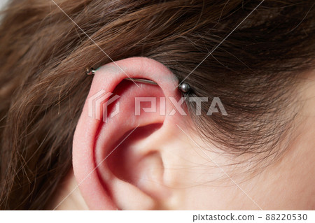 Stretched lobe piercing, grunge concept. Pierced woman ear with black plug tunnel. industrial and rook. 88220530