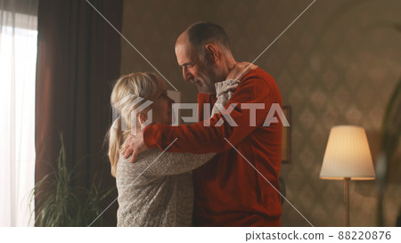 Cheerful retired couple dancing at home 88220876