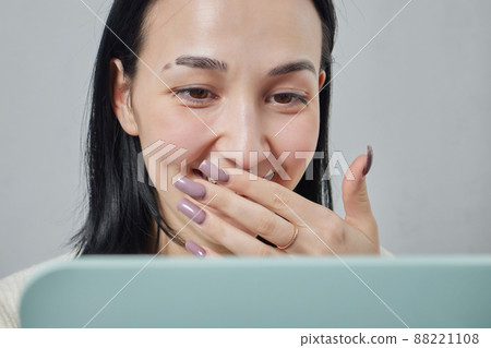 Closeup of a young woman's visage with piercing septum hanging from her nose. 88221108