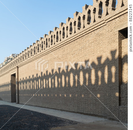 Stone bricks old decorated fence with wooden door and shadows of decorations of the opposite fence, Mosque of Ibn Tulun Stone bricks old decorated fence with wooden door and shadows of decorations of the opposite fence, Mosque of Ibn Tulun 88223145