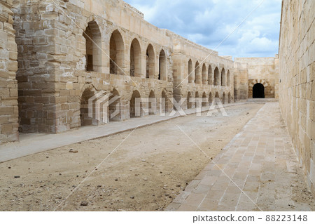 Stone bricks wall with embedded recessed arches at an old abandoned horse stall at the Citadel of Qaitbay, Alexandria, Egypt 88223148