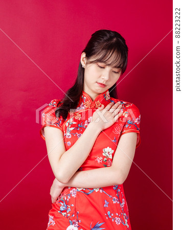 Beautiful asian woman wearing traditional cheongsam qipao dress with neck ache on red background. Beautiful asian woman wearing traditional cheongsam qipao dress with neck ache on red background. 88223222