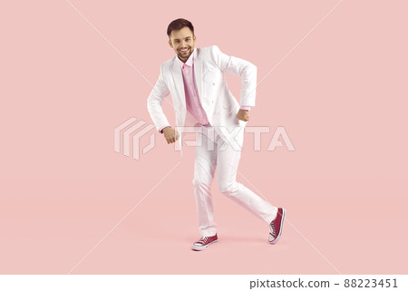Cheerful trendy guy in white formal suit funny dancing isolated on pastel pink background. 88223451