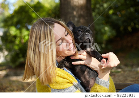 woman sitting on a bench with french bulldog 88223935