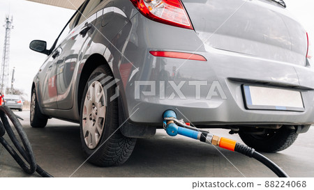 Person pumping gas. Fuel petrol for car at gasoline oil station nozzle in tank. Hand and black refueling gun close-up. 88224068