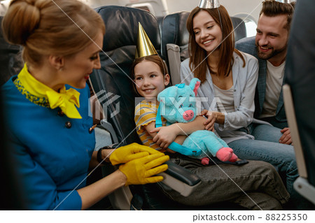 Family celebrating kid birthday and talking with stewardess in plane 88225350