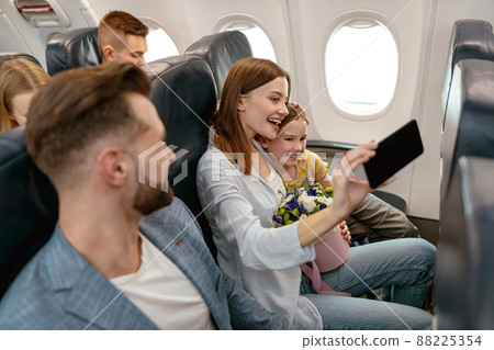 Cheerful woman and child making selfie in airplane Cheerful woman and child making selfie in airplane 88225354