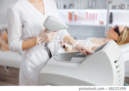 Woman beautician using laser epilation machine in beauty salon 88225399