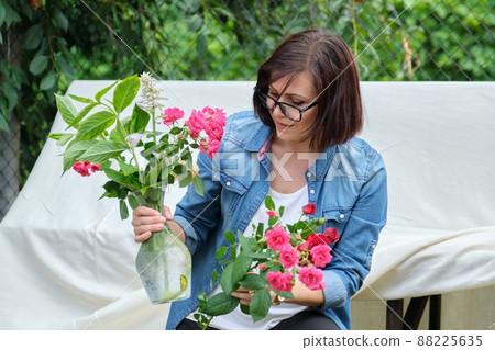 Woman making bouquet of flowers in vase outdoor 88225635