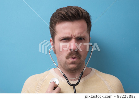 Caucasian patient with mustache listening to his heart beating. Self control. Studio shot Caucasian patient with mustache listening to his heart beating. Self control. Studio shot 88225882