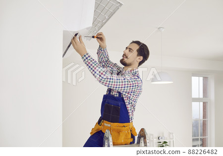 Young male professional repairman installs new air conditioner in client's apartment. Young male professional repairman installs new air conditioner in client's apartment. 88226482