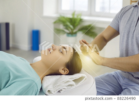 Woman relaxing and restoring energy during holistic healing session with Reiki therapist Woman relaxing and restoring energy during holistic healing session with Reiki therapist 88226490