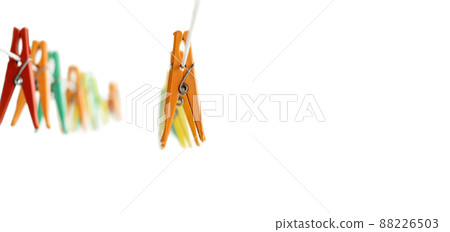 Multicolored clothespins for drying clean washed clothes hang on a clothesline on the side on a white background. Copy space. Banner Multicolored clothespins for drying clean washed clothes hang on a clothesline on the side on a white background. Copy space. Banner 88226503