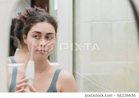 an attractive girl uses a darsonval device against acne .cares for skin from youth. with copy space 88226636