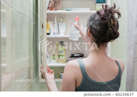 Beautiful girl choosing beauty products from the bathroom shelf and take it Beautiful girl choosing beauty products from the bathroom shelf and take it 88226637