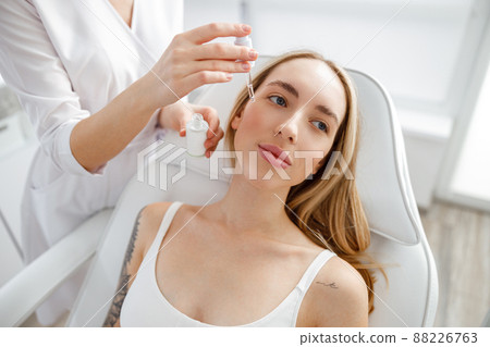 Beautician applying vitamin serum on woman face Beautician applying vitamin serum on woman face 88226763