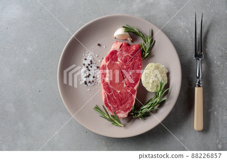 Raw beef steak with rosemary, garlic, salt, and pepper. 88226857