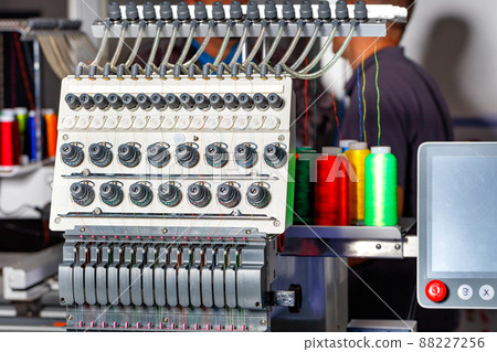 Programmable industrial embroidery machine with multi colored threads and tension system. Closeup, selective focus. Programmable industrial embroidery machine with multi colored threads and tension system. Closeup, selective focus. 88227256