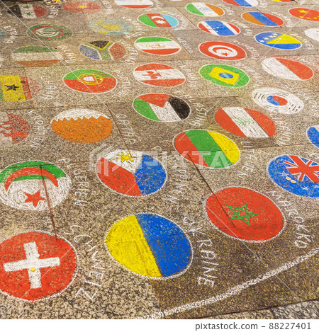 Colorful emblems, flags of different countries painted on pavement with multicolored crayons 88227401