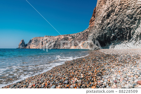 view of the sunset sea and the beach, the volcanic rock is lit by the warm sunset, sand and pebbles, volcanic basalt as in Iceland. Copy space. The concept of calmness, silence and unity with nature. view of the sunset sea and the beach, the volcanic rock is lit by the warm sunset, sand and pebbles, volcanic basalt as in Iceland. Copy space. The concept of calmness, silence and unity with nature. 88228509