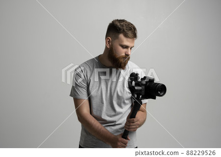 Bearder videographer filmmaker cinematographer dop with 3-axis gimbal and dslr camera. Filmmaking, videography, hobby and creativity concept. 88229526