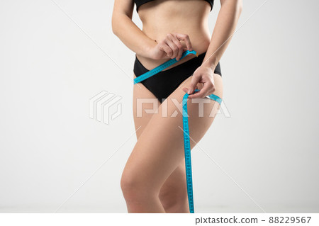 Healthy female body with measuring tape. The girl taking measurements of her body on white background. 88229567