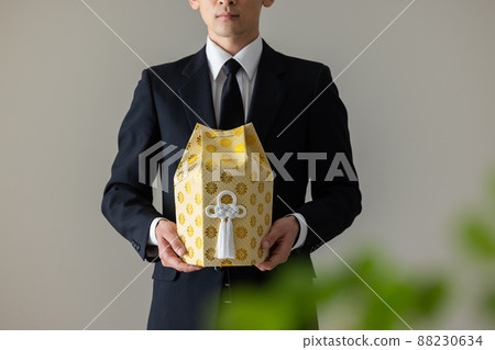 A man in mourning dress holding his ashes 88230634