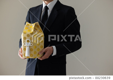 一個穿著喪服的男人拿著他的骨灰 88230639