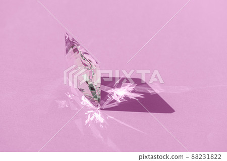 Crystal prism with light diffraction of spectrum colours and reflection with trendy light and hard shadows on pink background. Light spectrum reflected through glass prism. 88231822
