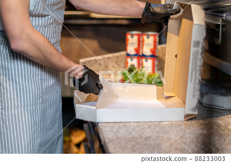 A baker packing pizza in the kitchen A baker packing pizza in the kitchen 88233003