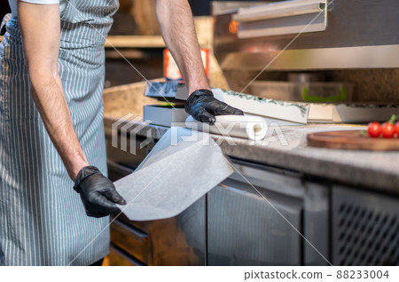 A baker packing pizza in the kitchen A baker packing pizza in the kitchen 88233004
