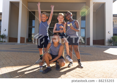 Cheerful elementary schoolboys against school building during sunny day 88233203