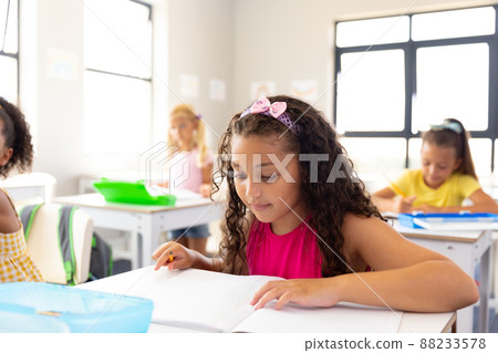 Multiracial elementary schoolgirls studying at desk in classroom Multiracial elementary schoolgirls studying at desk in classroom 88233578